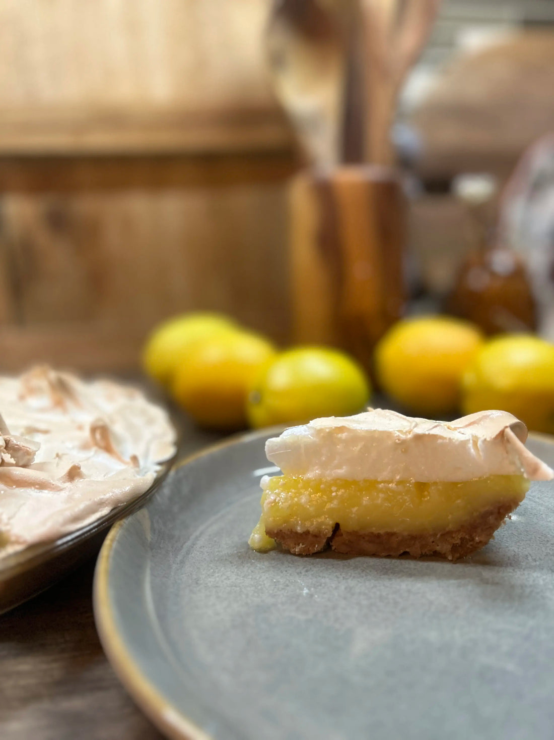 slice of Bianca's lemon meringue pie in front of lemons